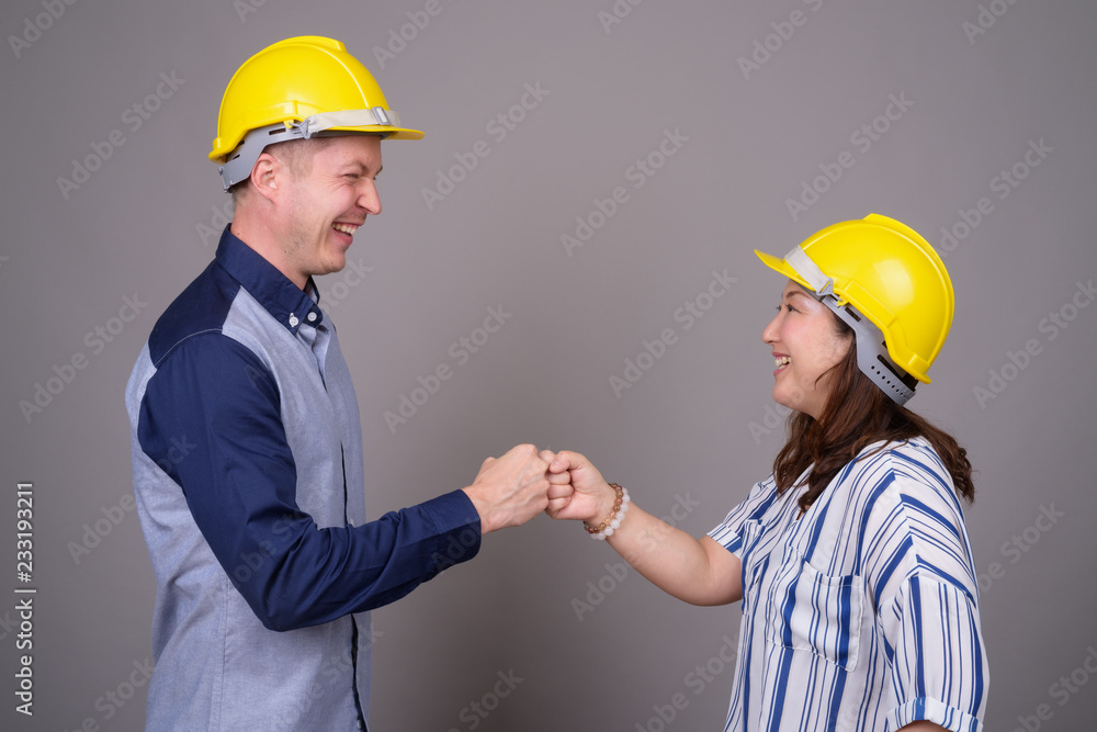 Businessman and mature Asian businesswoman wearing hardhat Businessman and mature Asian businesswoman wearing hardhat