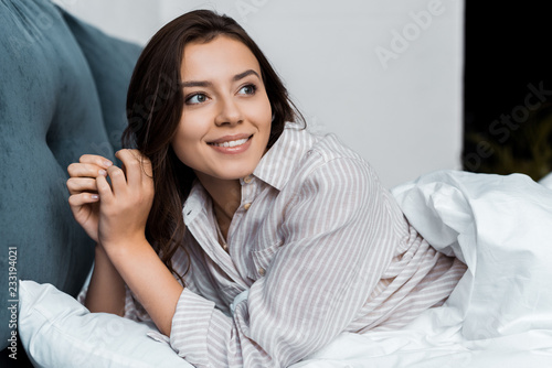 attractive smiling girl in pajamas lying in bed in the morning