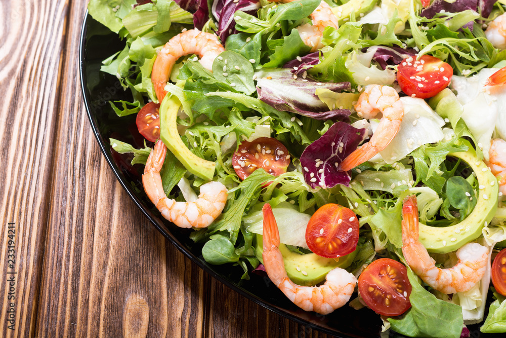 Mix of salad with shrimps , avocado and cherry tomatoes . Healthy food background Mix of salad with shrimps , avocado and cherry tomatoes . Healthy food background