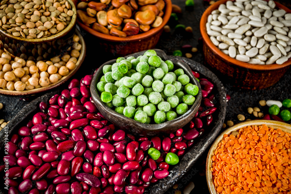 Various assortment of legumes - beans, soy beans, chickpeas, lentils, green peas. Healthy eating concept. Vegetable proteins. White marble background copy space top view