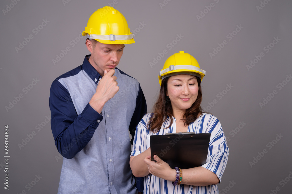 Businessman and mature Asian businesswoman wearing hardhat Businessman and mature Asian businesswoman wearing hardhat