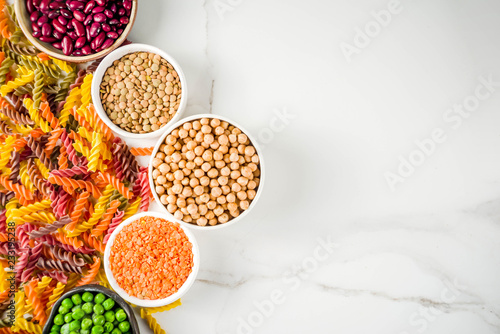 Trend healthy food, vegan diet concept. Multi colored legume pasta with raw beans. Beans, chickpeas, green peas, lentils. Copy space top view