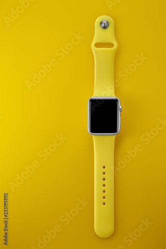 Silver Apple Watch with yellow sport band on a yellow background
