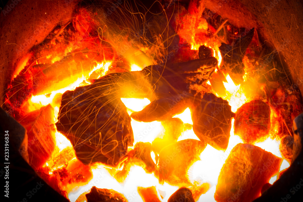 Fototapeta premium burning charcoal background with fire and sparks.Coals burning flameless in fireplace.flames of fire with sparks background.Live Coals .Beautiful in soft and blur style for background.