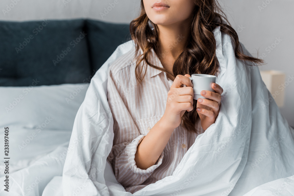 cropped view of girl with cup of coffee in bed in the morning cropped view of girl with cup of coffee in bed in the morning