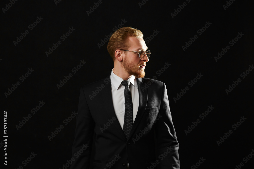 Close up portrait of successful man with beard in glasses. Confident young businessman looking aside on black background with copy space. Close up portrait of successful man with beard in glasses. Confident young businessman looking aside on black background with copy space.