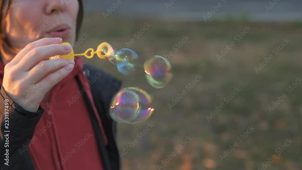 Woman blowing soap bubbles outdoor, close up slow motion Woman blowing soap bubbles outdoor, close up slow motion
