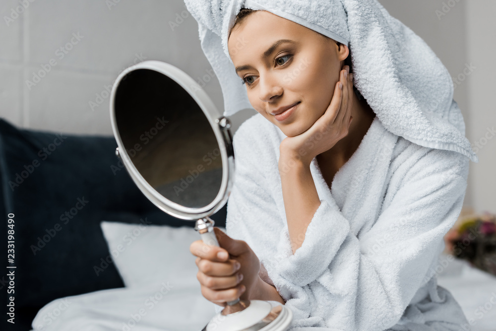 beautiful smiling girl in white towel looking at her face in mirror beautiful smiling girl in white towel looking at her face in mirror