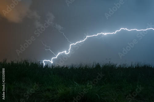 A powerful horizontal lightning bolt curves and strikes down to the earth