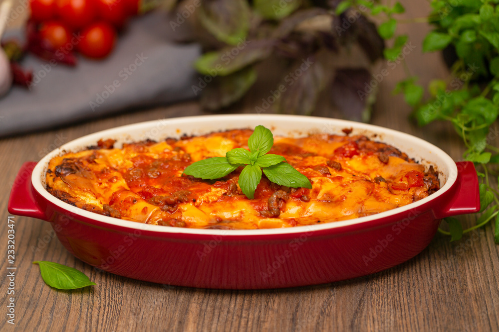 Italian food. Hot tasty freshly baked lasagna served with basil herb on wooden table. Italian food. Hot tasty freshly baked lasagna served with basil herb on wooden table.
