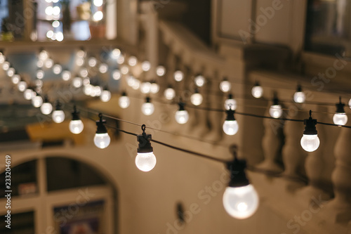 light bulbs garland. cafe exterior decor. closeup rows of lamps perspective with bokeh