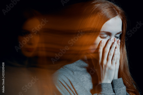 Blurred picture of young beautiful redhead girl with depression covering her mouth