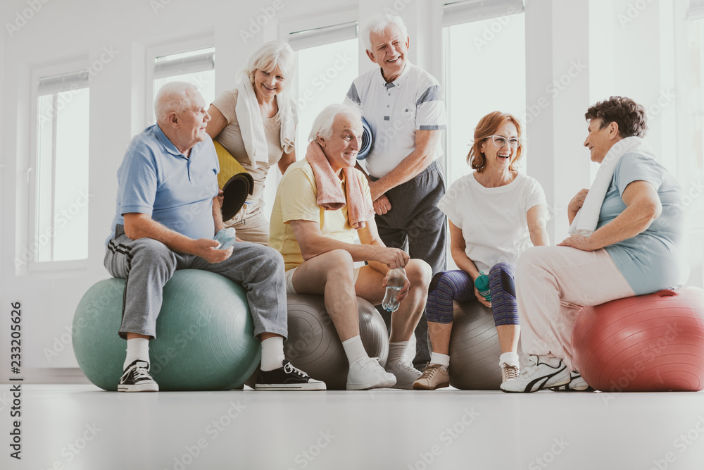 Obraz premium Low angle on smiling senior people on balls after gymnastic classes at sport club