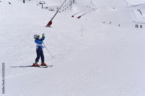 A boy in a blue ski jumpsuit skiing from the snowy mountains of the Sierra Nevada