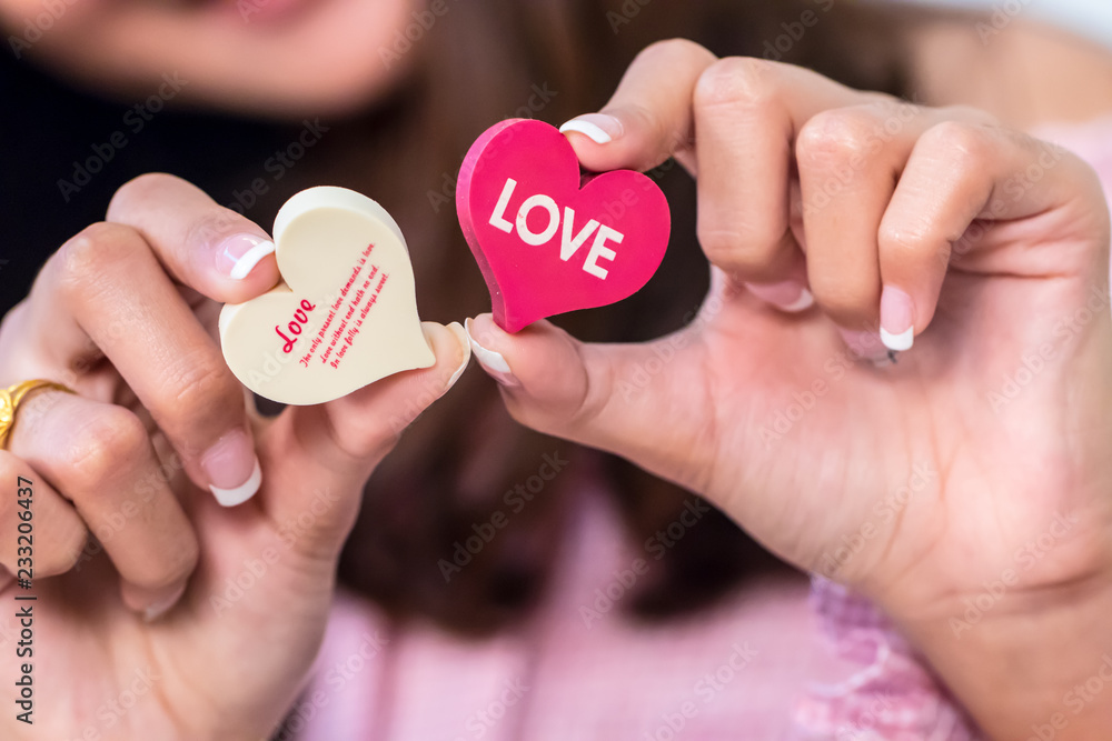 Single red heart isolated with word LOVE keep by two fingers, close up and background blur style.symbol of love and valentines day. can be use to greeting card and background for special event. Single red heart isolated with word LOVE keep by two fingers, close up and background blur style.symbol of love and valentines day. can be use to greeting card and background for special event.
