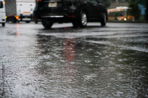 Heavy rain falls on asphalt with blurry cars (focus on road surface)
