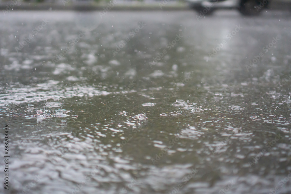 Fototapeta premium Heavy rain falls on asphalt with blurry cars (focus on road surface)