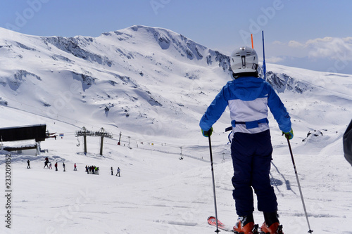 A boy in a blue  ski jumpsuit skiing from the snowy mountains of the Sierra Nevada