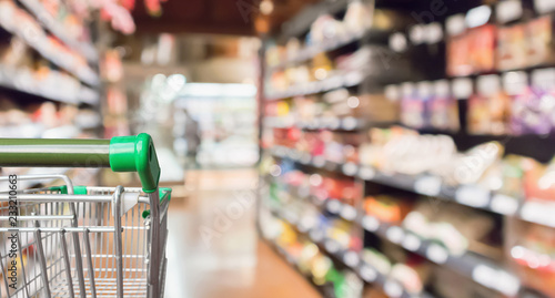 Empty green supermarket shopping cart with abstract blur grocery store aisle defocused background photo