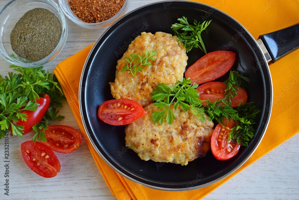 Delicious fried cutlets with tomatoes and herbs in a frying pan. Delicious fried cutlets with tomatoes and herbs in a frying pan.