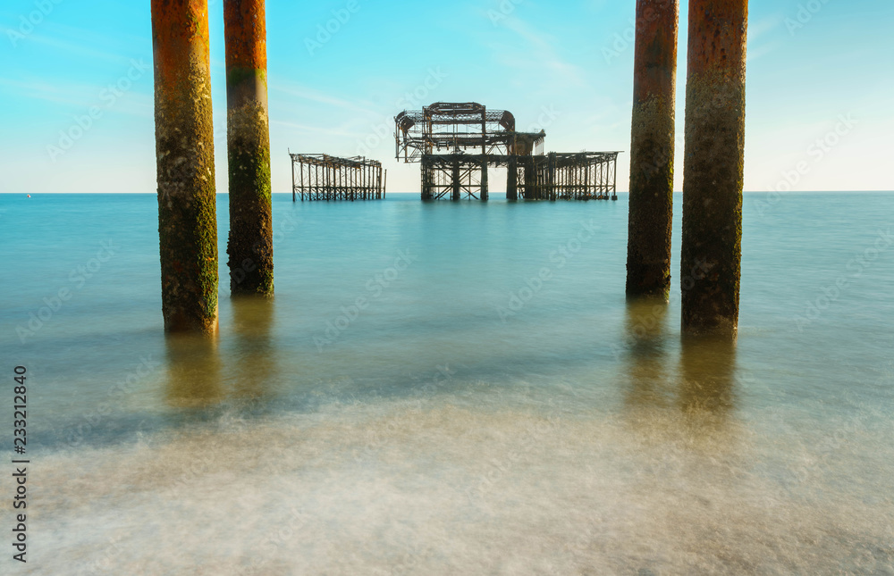 The old remains of Brighton Pier left standing in sea with beautiful waves in Brighton and Hove's West Pier. Old vintage West Pier Brighton Beach.