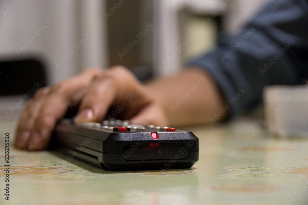 Fototapeta premium Turning on the TV and switching channels with a female hand remote control
