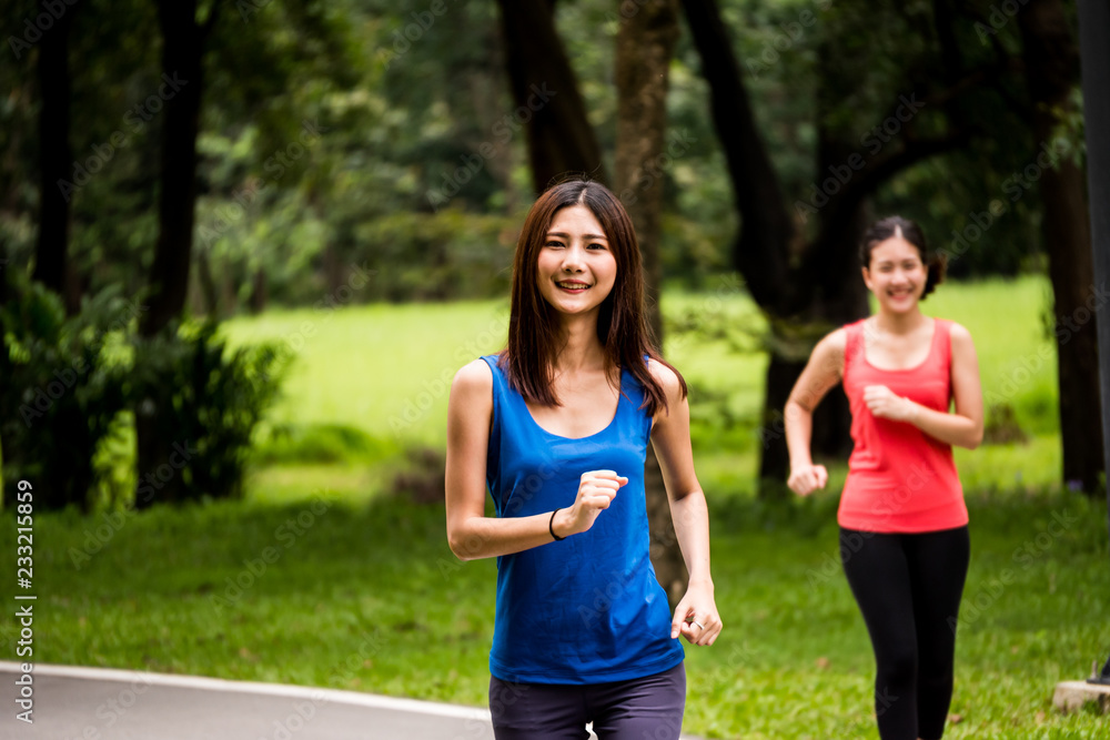 Portrait of young girl jogging in a park with her friend Portrait of young girl jogging in a park with her friend