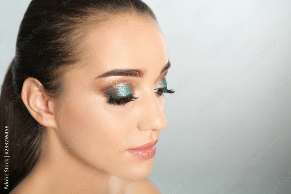 Naklejka premium Portrait of young woman with eyelash extensions and makeup on light background. Space for text