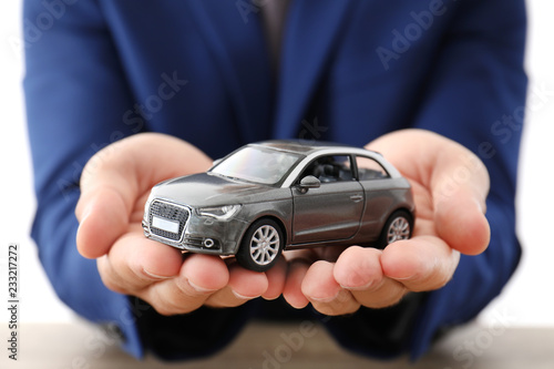 Insurance agent holding toy car over table, focus on hands