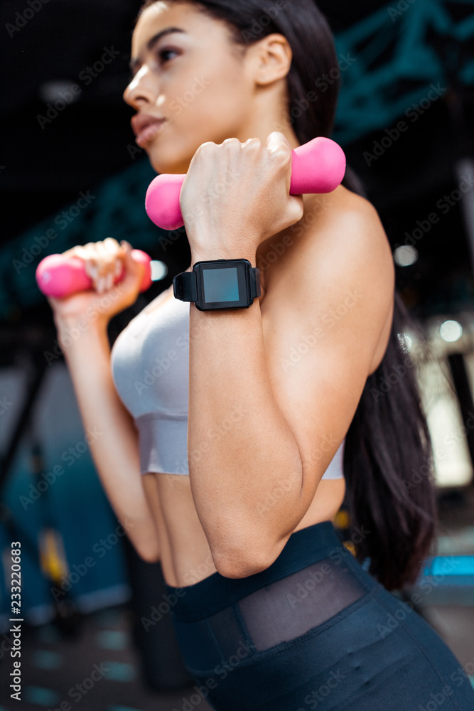 Close up of strong sportive girl working out with dumbbells in fitness gym Close up of strong sportive girl working out with dumbbells in fitness gym