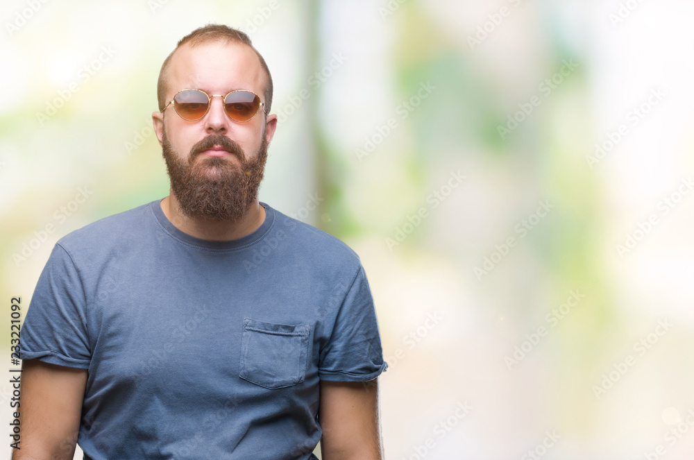 Young caucasian hipster man wearing sunglasses over isolated background cheerful with a smile of face pointing with hand and finger up to the side with happy and natural expression on face Young caucasian hipster man wearing sunglasses over isolated background cheerful with a smile of face pointing with hand and finger up to the side with happy and natural expression on face
