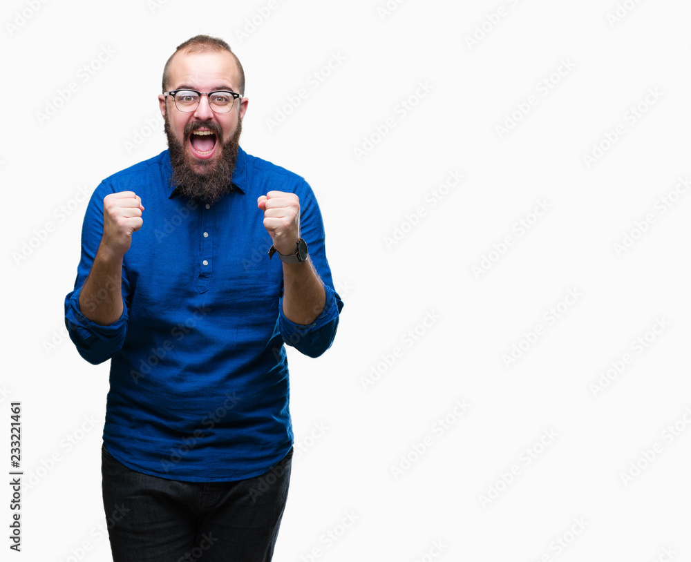 Young caucasian hipster man wearing glasses over isolated background celebrating surprised and amazed for success with arms raised and open eyes. Winner concept. Young caucasian hipster man wearing glasses over isolated background celebrating surprised and amazed for success with arms raised and open eyes. Winner concept.