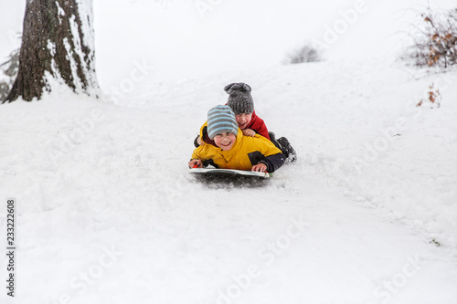 cheerful children slide down hills on sled. boys having fun in the snow