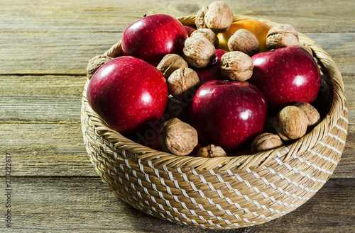 red ripe apples and nuts in a basket on a tree background