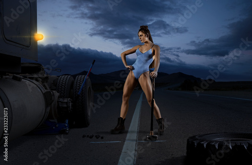 Woman trucker replace tire on wheel photo