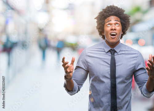 Afro american business man over isolated background crazy and mad shouting and yelling with aggressive expression and arms raised. Frustration concept.