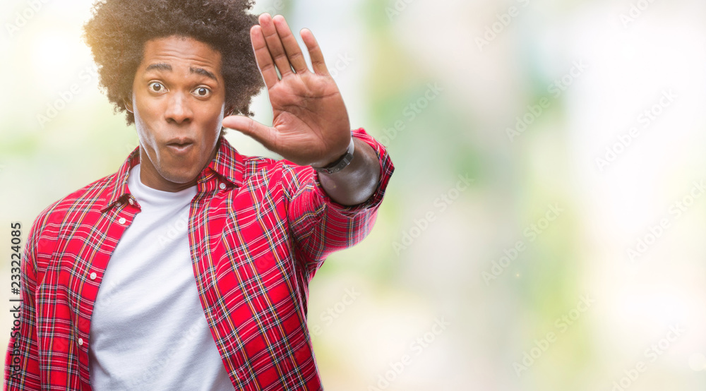 Naklejka premium Afro american man over isolated background doing stop sing with palm of the hand. Warning expression with negative and serious gesture on the face.