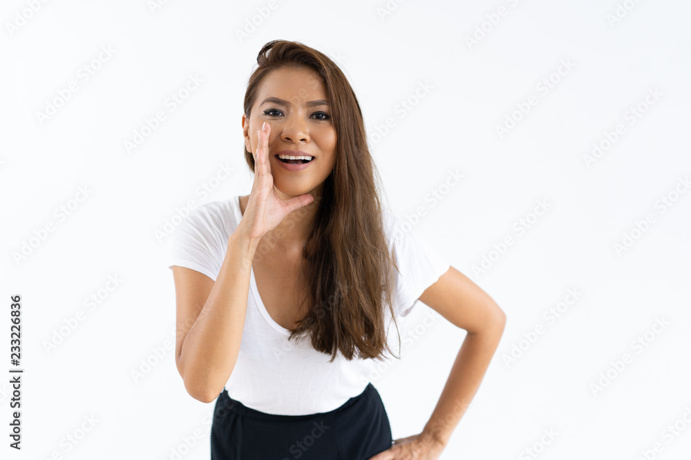 Cheerful girl sharing secret. Front view of young woman smiling and speaking with hand at mouth. Announcement or gossip concept Cheerful girl sharing secret. Front view of young woman smiling and speaking with hand at mouth. Announcement or gossip concept