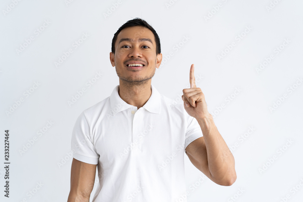 Joyful student having brilliant idea. Smiling Latin man dressed in white polo pointing finger up. Presentation concept Joyful student having brilliant idea. Smiling Latin man dressed in white polo pointing finger up. Presentation concept