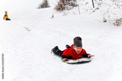 children have fun in the snow. happy child sledding down the hill