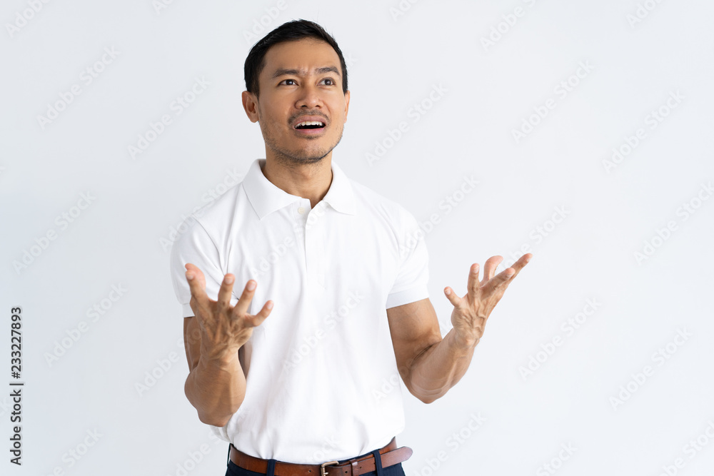 Shocked guy staring into distance and gesturing emotionally. Young mix raced man dressed in white polo excited with scene. Shock and surprise concept Shocked guy staring into distance and gesturing emotionally. Young mix raced man dressed in white polo excited with scene. Shock and surprise concept