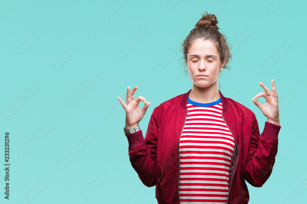 Beautiful brunette curly hair young girl wearing a jacket over isolated background relax and smiling with eyes closed doing meditation gesture with fingers. Yoga concept. - obrazy, fototapety, plakaty 