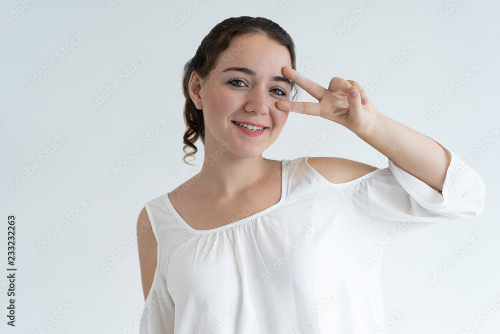 Playful lovely woman showing victory sign and looking at camera. Smiling young lady. Carefree woman concept. Isolated front view on white background. Playful lovely woman showing victory sign and looking at camera. Smiling young lady. Carefree woman concept. Isolated front view on white background.