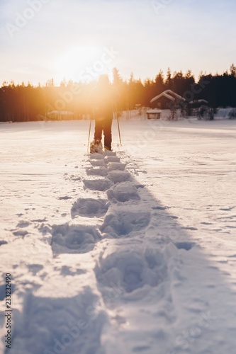 Man in snowshoes is walking with beautiful sunrise light. © nblxer