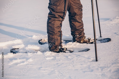 Man with snowshoe on the snow path close-up. Man in snowshoes with trekking poles in Finland © nblxer