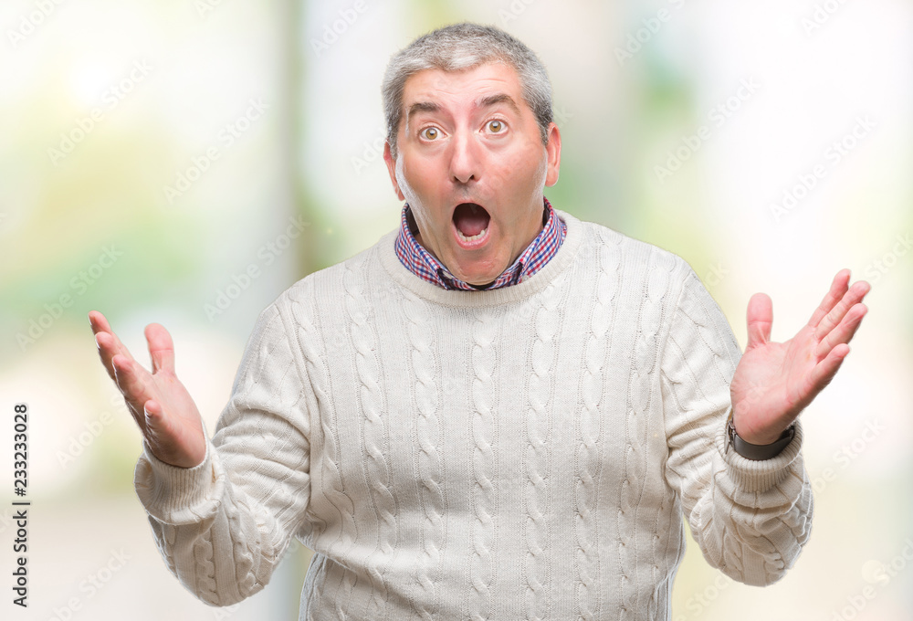 Handsome senior man wearing winter sweater over isolated background celebrating crazy and amazed for success with arms raised and open eyes screaming excited. Winner concept Handsome senior man wearing winter sweater over isolated background celebrating crazy and amazed for success with arms raised and open eyes screaming excited. Winner concept