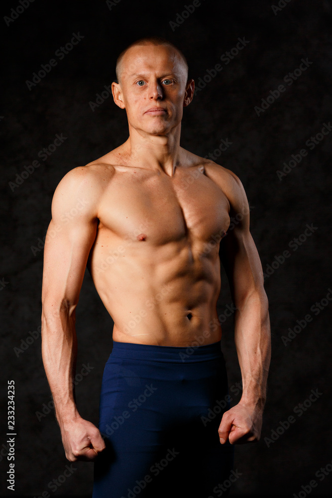 Handsome muscular man posing on dark background
