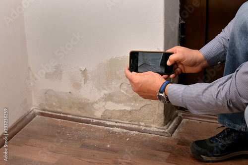Foto A man from an insurance company makes a photo of a damaged wall