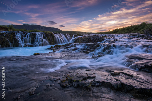 Braurfossar is amazing waterfall with colorful clouds and blue sky over