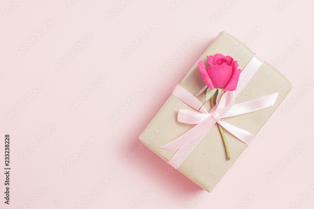 Gift box with rose on pink bacground.